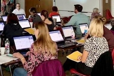 A classroom full of people working on laptop computers