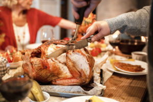 Whole turkey being carved at holiday table. 