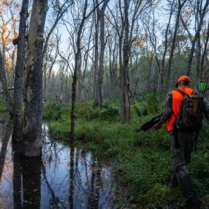Hunter walking by water in Sam Houston National Forrest
