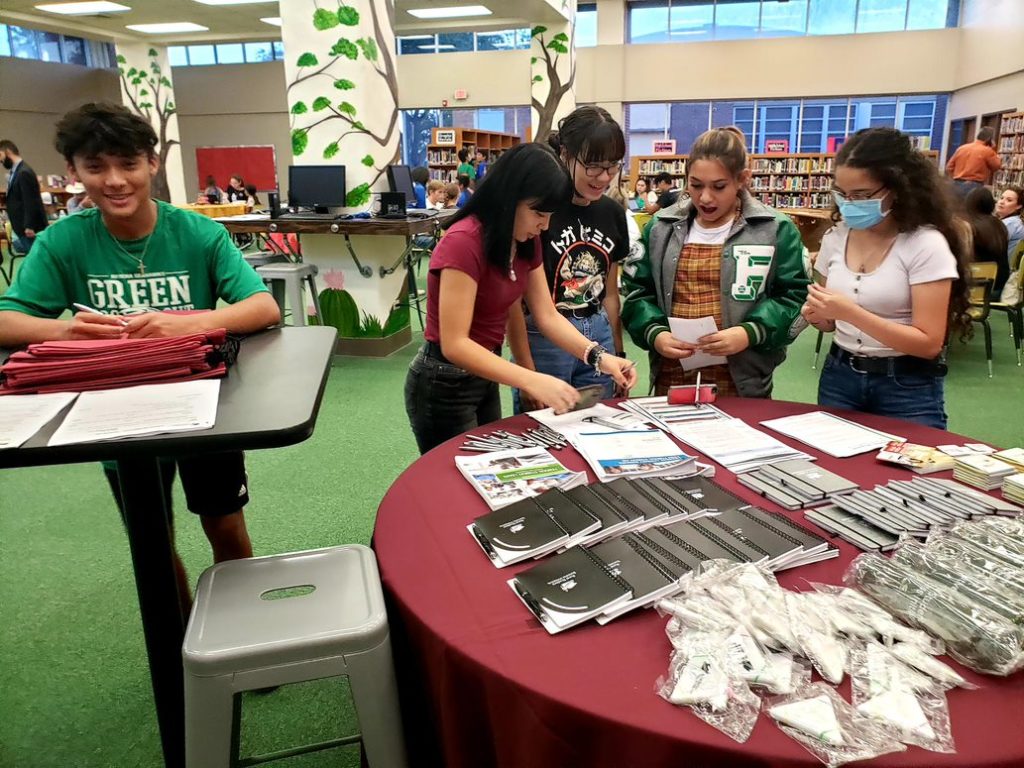 Students at Kaufer Early College High School in the Riviera ISD gather around a table stocked with handouts and brochures