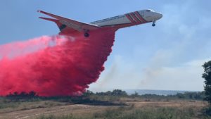 Air tanker dropping a plume of red fuel retardant