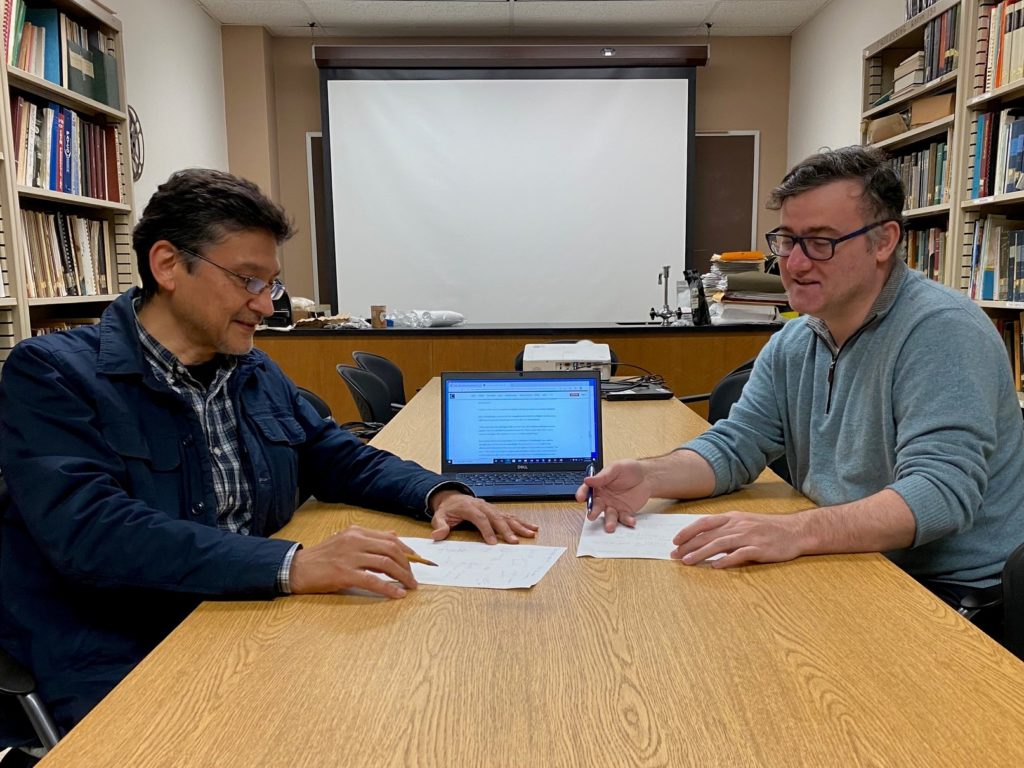 Two men, Drs.  Cisneros-Zevallos and Akbulut, plan the development of fruit and vegetable equipment smart surfaces and coatings at a table in an office setting.
