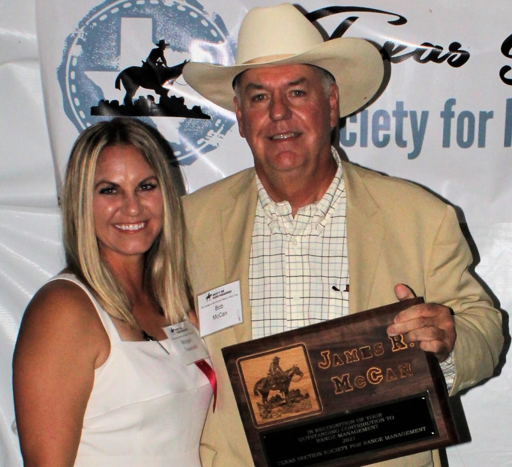 Dr. Morgan Treadwell presents the Outstanding Contribution to Rangeland Management to Bob McCan, Victoria. She wears a white jumpsuit and he wears a cowboy hat and holds his award plaque.