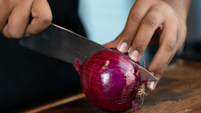 knife and hand cutting red onion