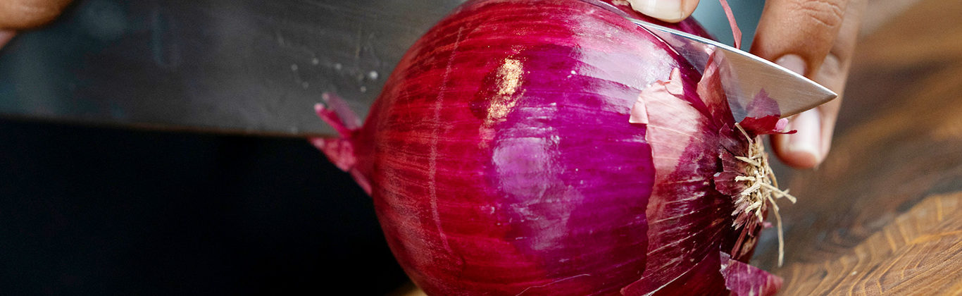 knife and hands cutting red onion