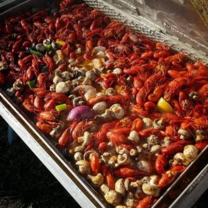 A large basket of crawfish cooking with potatoes and mushrooms