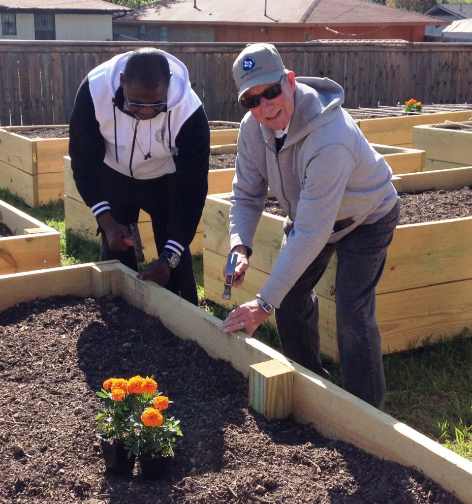 Two men building a raised bed box in a community garden