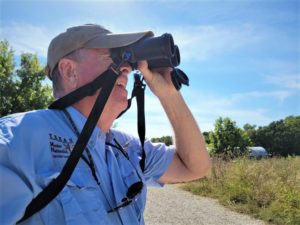 A man who is a Texas Master Naturalist looks through binoculars. 