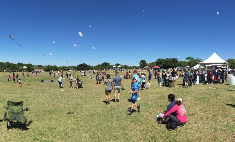People out on a lawn with chairs and tents at Kite Fest
