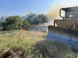 Brush pile on fire with dozer in front 