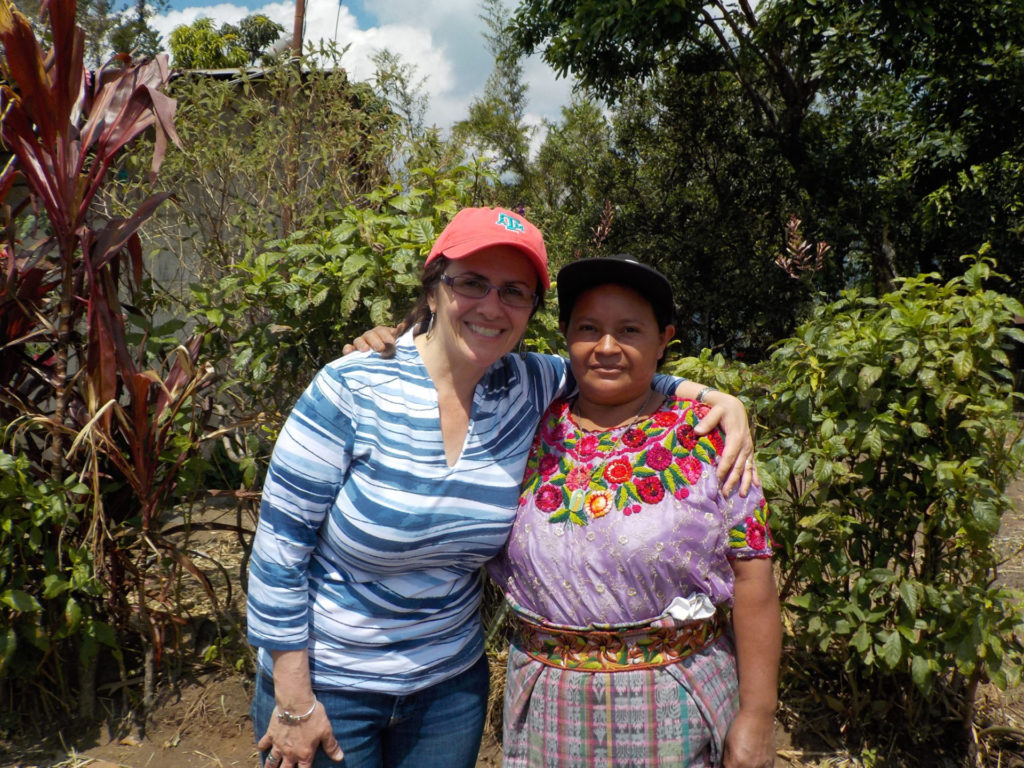 Two women with arms around shoulders standing in a coffee field