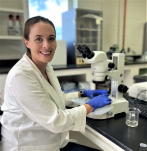 A woman, Dr. Anjel Helms, sits in her lab