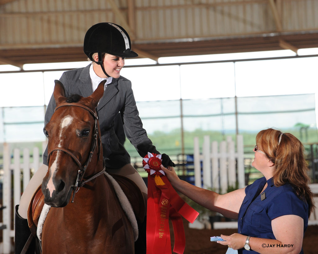 Girl on horse receiving ribbon at Texas State 4-H Horse Show.