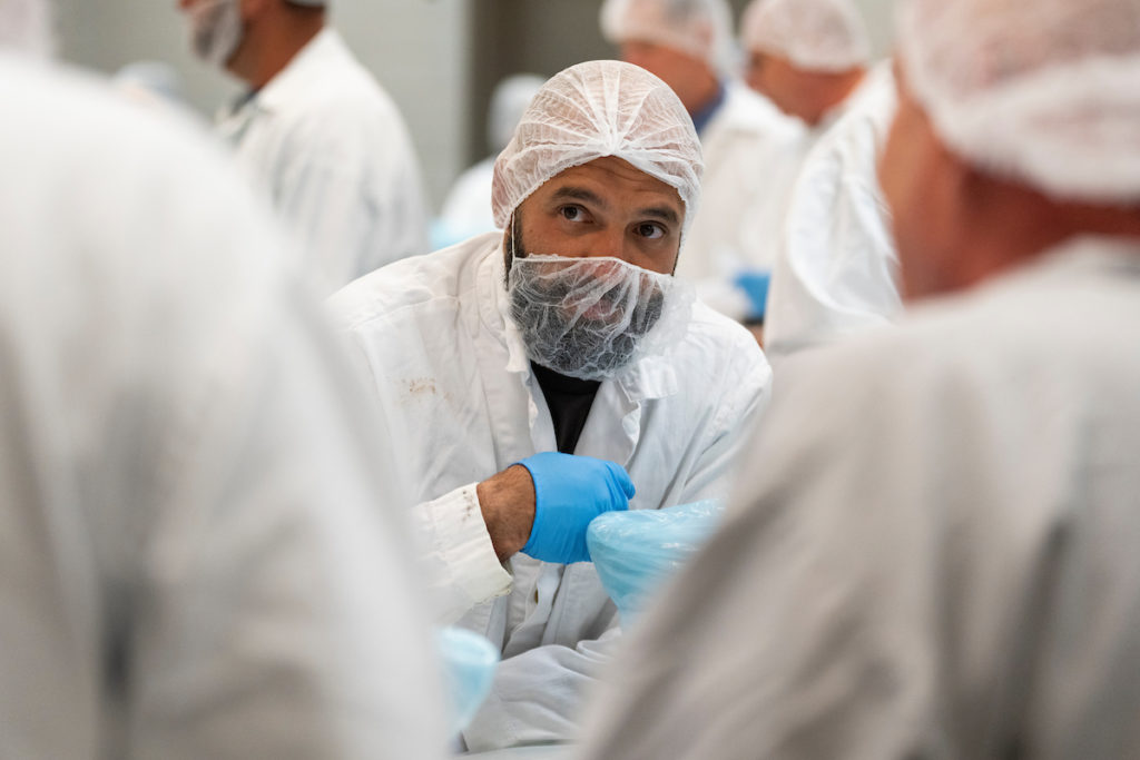 a man in a hair net and blue gloves listening to speaker
