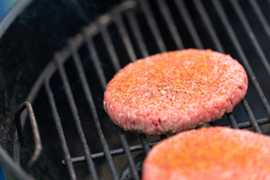 two raw hamburger patties on a grill