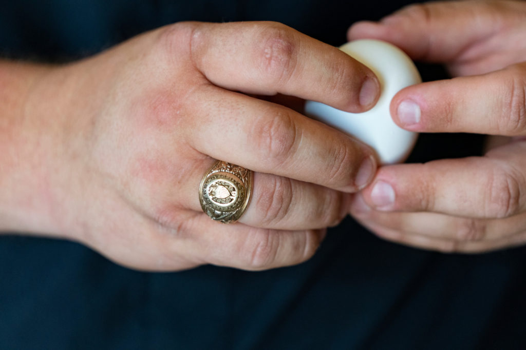Close up of hands, one with an Aggie ring, holding an egg to represent the Department of Poultry Science.
