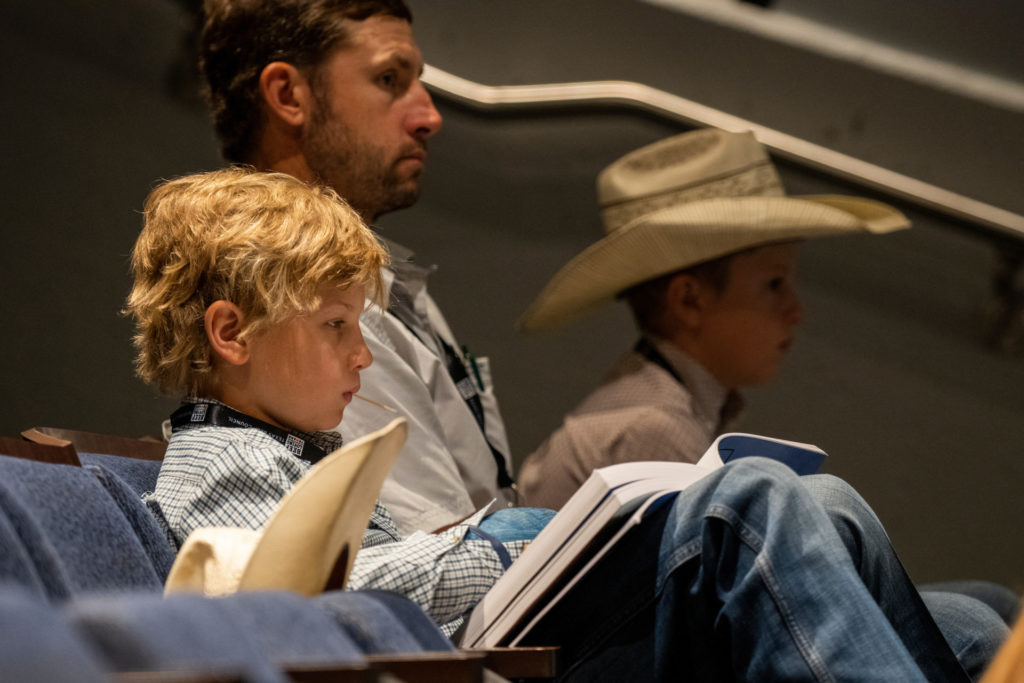 Ranchers both old and young sit listening to an educational program