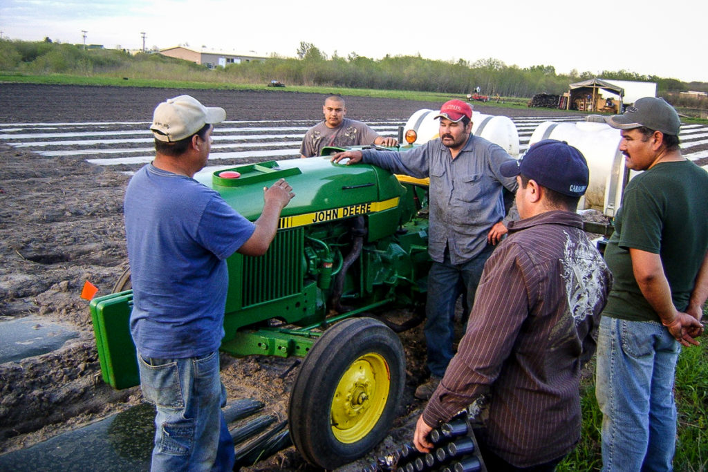 Group of Hispanic producers around tractor
