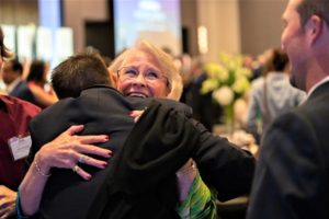A donor woman hugs a scholarship recipient. 