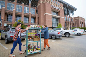 two floral design students pushing a cart of flower arrangements in front of Kyle Field