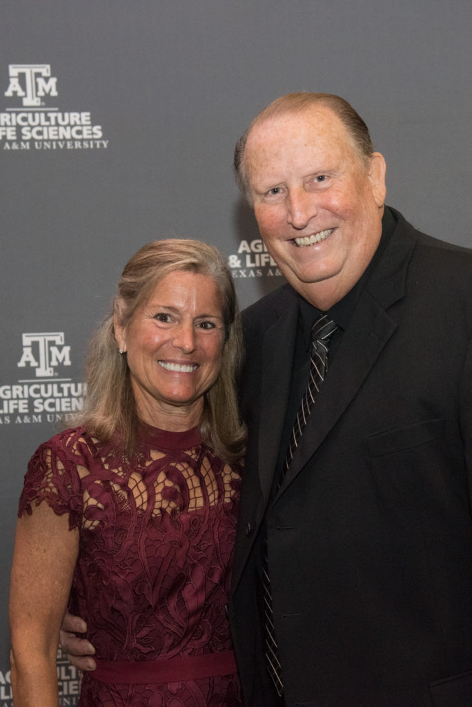 a woman in maroon and a man in a black suit - Chris and Joe Townsend - stand in front of a Texas A&M Agriculture and Life Sciences banner.