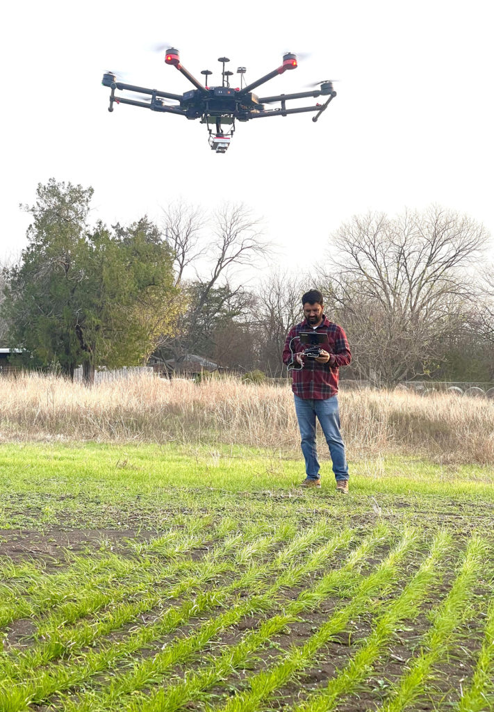 Gurjinder Baath flies a drone over a field with a growing cover crop shown as green plants in rows