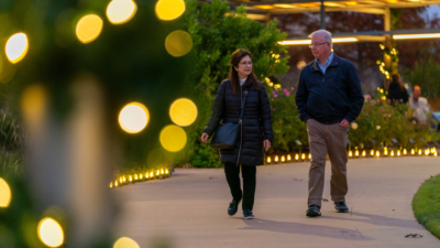 A couple walking outside on a path by outdoor lights