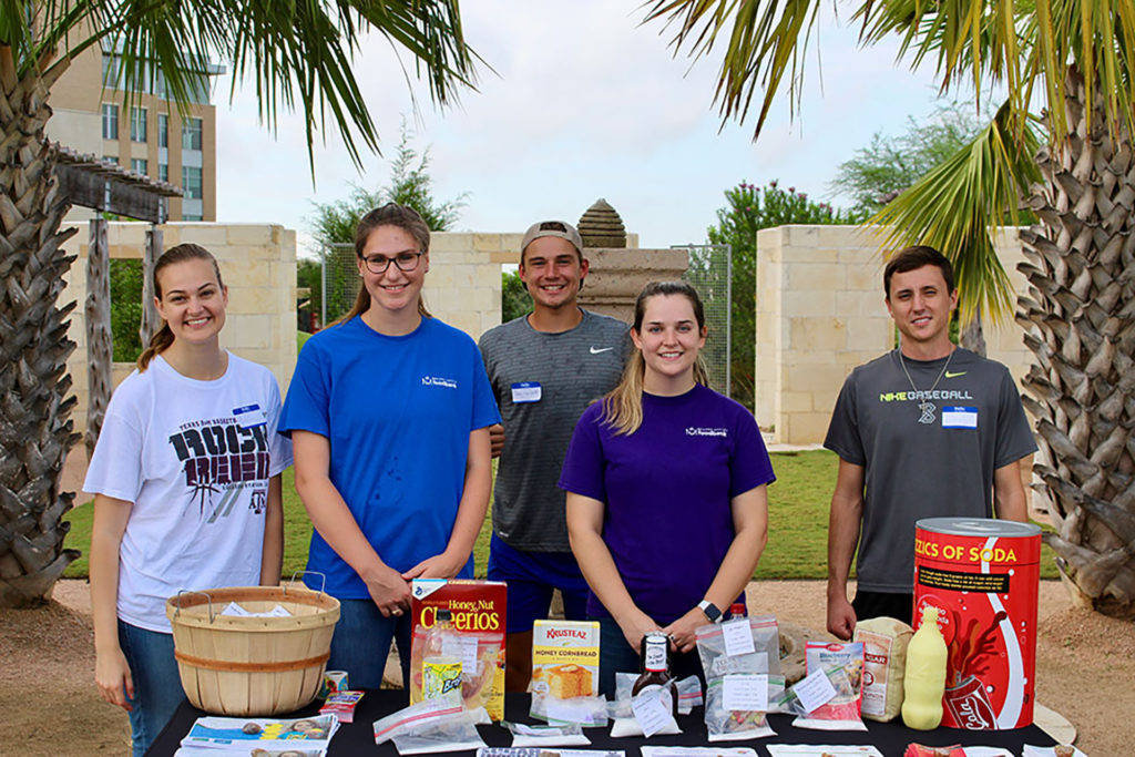 Male and female student volunteers at a REACH Project educational outreach table in the Leach Teaching Gardens.