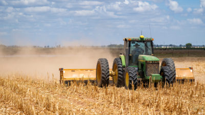 green tractor pulling a yellow drill in a field of crop stubble