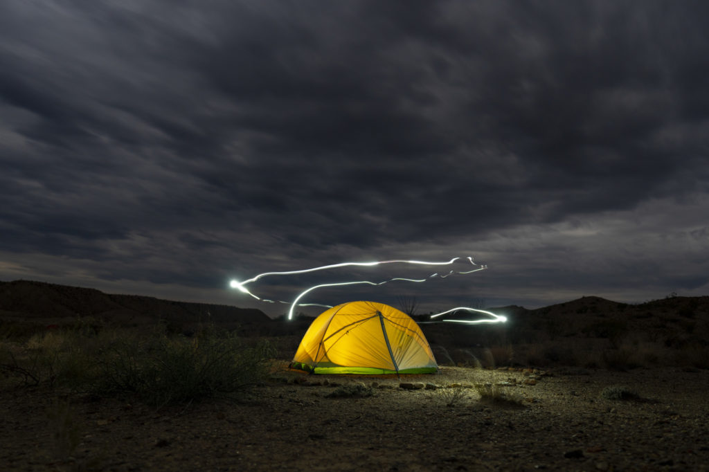Long exposure of flashlight trails around an illuminated tent