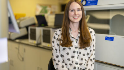 Lauren Cornell sits in her lab space and smiles