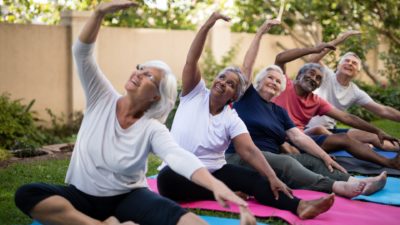 Senior people with arms raised exercising at park