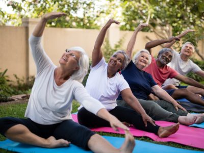 Senior people with arms raised exercising at park