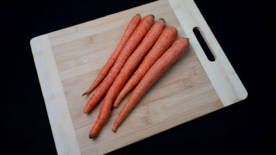 Fresh carrots on a cutting board. Their green tops have already been cut off,