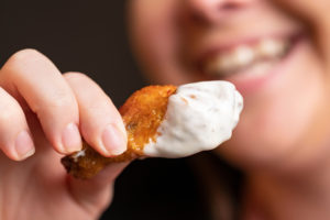 A chicken wing partially covered in dressing. 