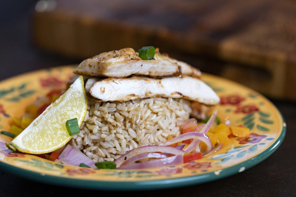 Healthy dish -- a plate of grilled chicken over whole grain rice.
