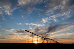 The silhouette of an irrigation pivot with the sunset in the background. 
