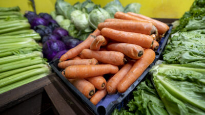 An assortment of fresh vegetables at a local-style market, including carrots, cabbage and lettuce.