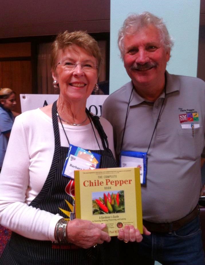 A woman and man pose together, holding a book titled: The Complete Chile Pepper Book