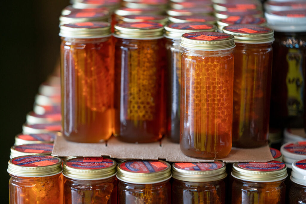 Un surtido de miel, frutas y mermeladas de la industria alimentaria casera enlatada a la venta en un mercado de granjeros.