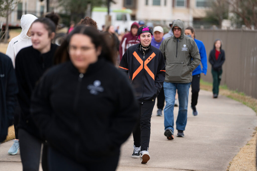 A group of people participating in the Walk Across Texas! program. It is a cold day and they wear jackets and hoods and  warm clothing. This is one of many programs Texas Master Wellness volunteers support.