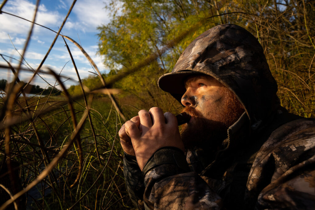 El hombre usa una llamada de pato mientras caza