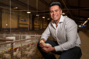 Daniel De Leon kneeling in a barn with chickens