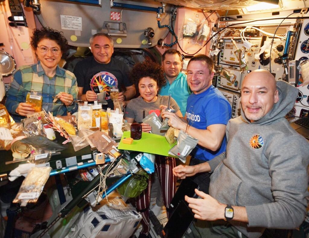 Crew of Inernational Space Station enjoying a Thanksgiving meal with a variety of space foods 