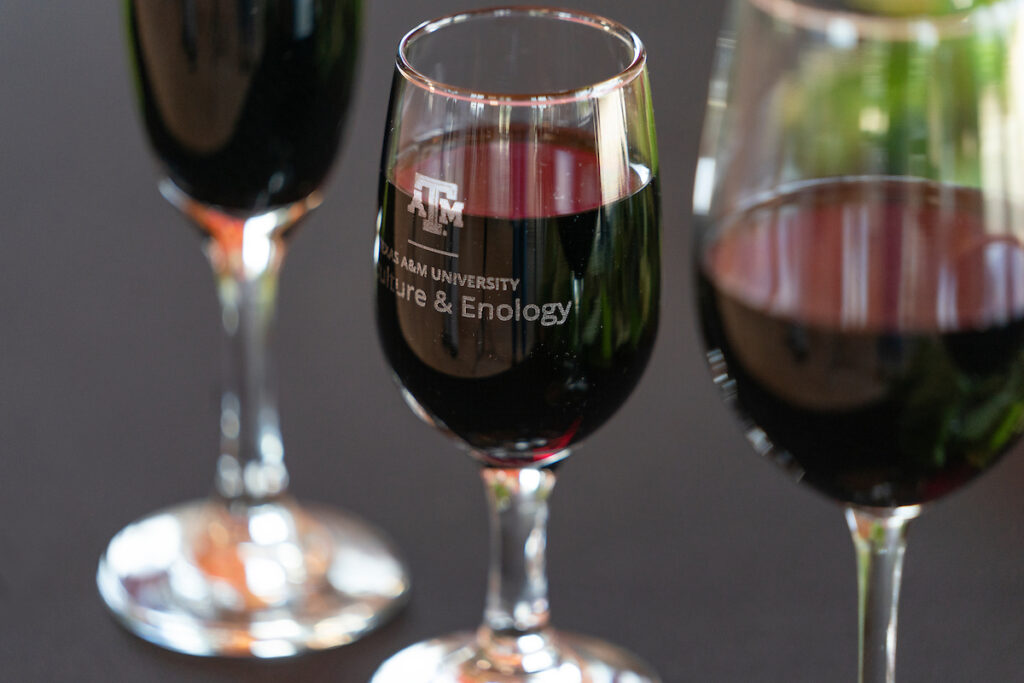 Copas de vino tinto con copas con el logo de Texas A&M y las palabras viticultura y enología