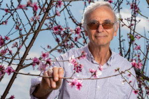 David Byrne, Ph.D, rodeado de melocotoneros en flor. 