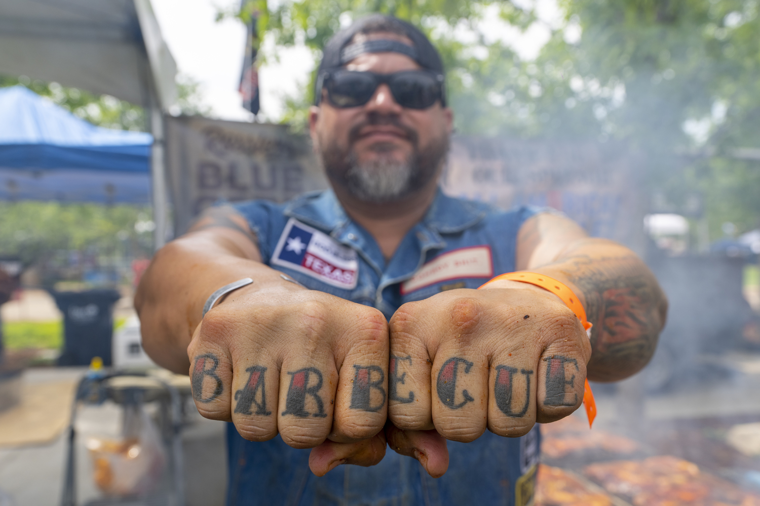 A man showing the letters to spell out barbecue tattooed on his knuckles