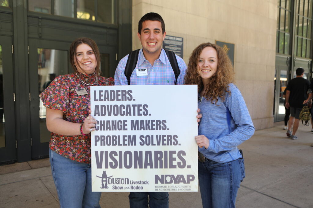 Tres personas juntas con un cartel que dice: liderazgo, defensores, creadores de cambios, solucionadores de problemas, visionarios. 