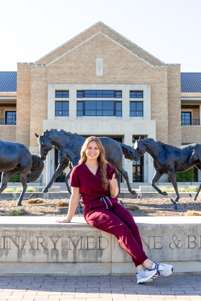 La estudiante Gracie Krejci sentada afuera del edificio de la Facultad de Medicina Veterinaria y Ciencias Biomédicas de Texas A&M. 