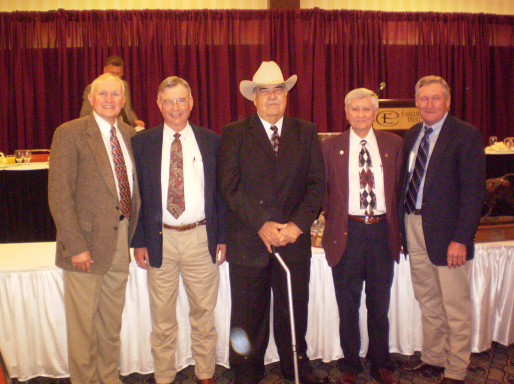 Five men in suits and ties pose for a 40th anniversary photo of their collegiate livestock judging team